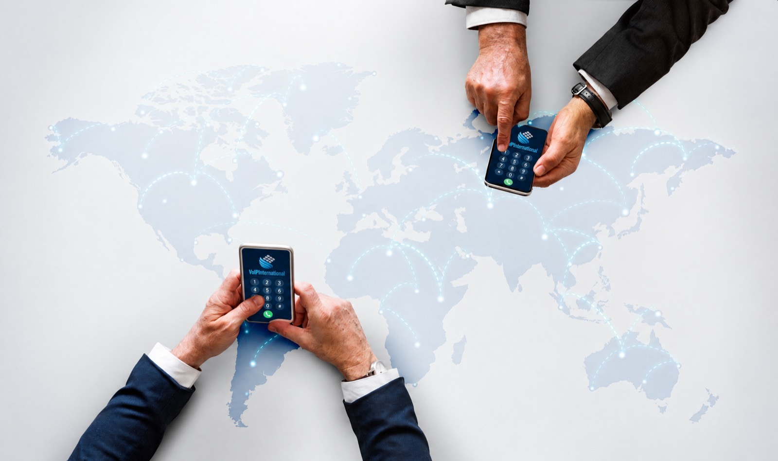 Two people holding phones over a world map