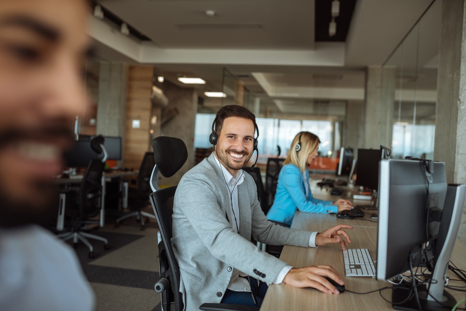 Smiling employee on a headset at his desk