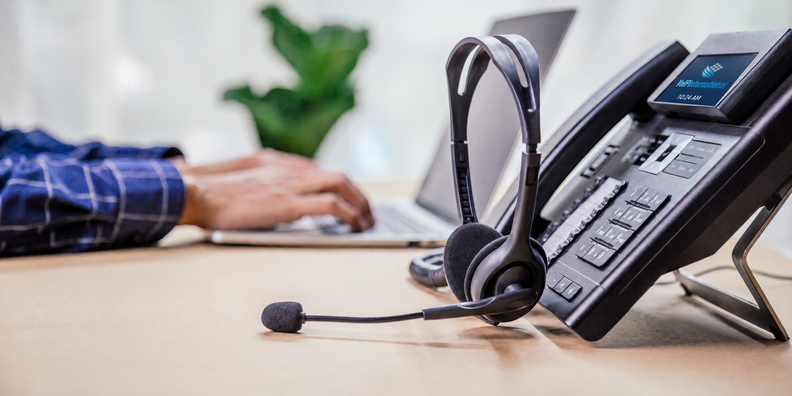 Headset beside a desk phone and laptop